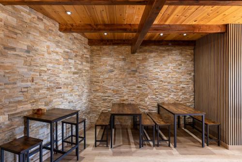 two tables and stools in a room with a brick wall at Alberg Taull in Taull