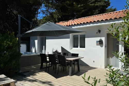 a patio with a table and chairs and an umbrella at Villa Thaïlande - Domaine Le Sherwood in Notre-Dame-de-Monts