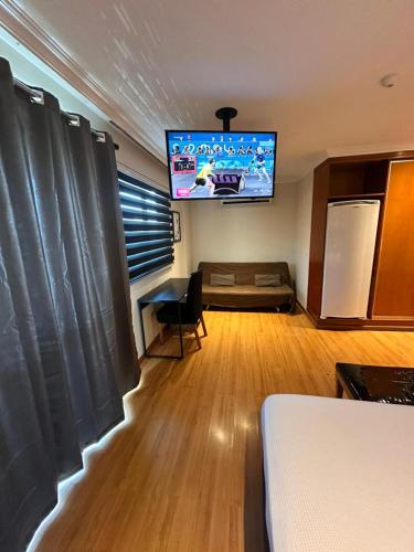 a room with a bed and a flat screen tv at Barra da Tijuca - 508 - De Frente para Maravilhosa Piscina - Estacionamento Gratuito - Academia Comphania Atletica - Balsa para Praia Grátis - Microondas - Geladeira Grande - Recepção 24horas - Wi-Fi - Com Pia in Barra da Tijuca