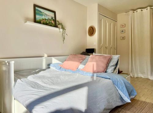 a bedroom with a bed with two pink pillows on it at Beautiful studio terrace with Esparron lake view 4 people in Esparron-de-Verdon
