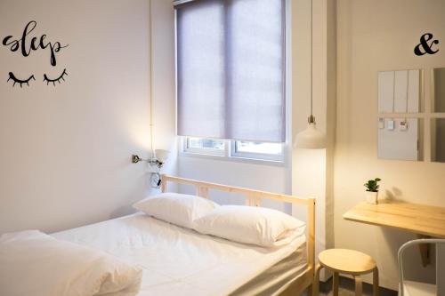 a bedroom with a bed with white sheets and a window at Movylodge in Bangkok