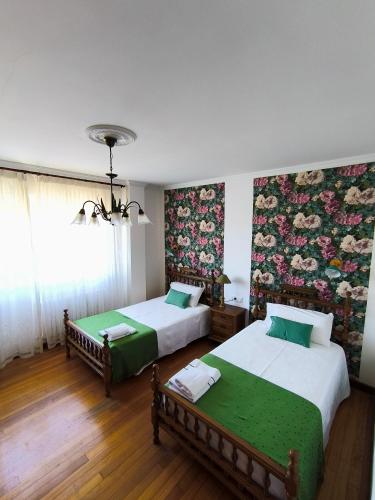 a bedroom with two beds and a wall with flowers at Arrochela apartamento in Ribeira