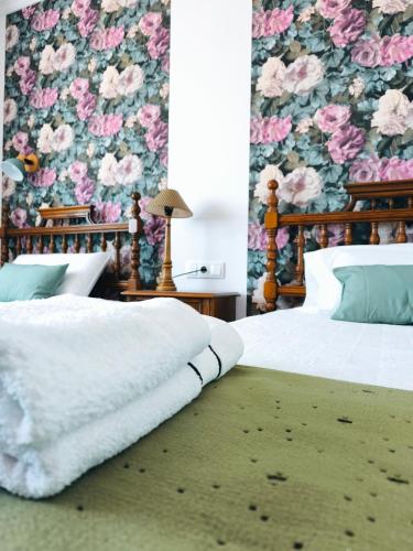 a bedroom with two beds with a floral wallpaper at Arrochela apartamento in Ribeira