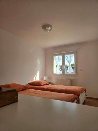 deux lits dans une chambre blanche avec une fenêtre dans l'établissement La maison des lavandes, à Cléon-dʼAndran