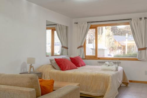 a bedroom with a bed with red pillows and a window at Depto Del lago, con la mejor vista y cercano a todo - Ayres del Bosque Alojamientos in San Martín de los Andes