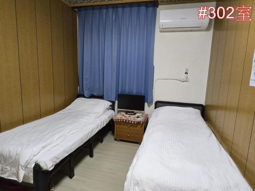 two beds in a room with blue curtains at 高鐵中彰309民宿 in Changhua City