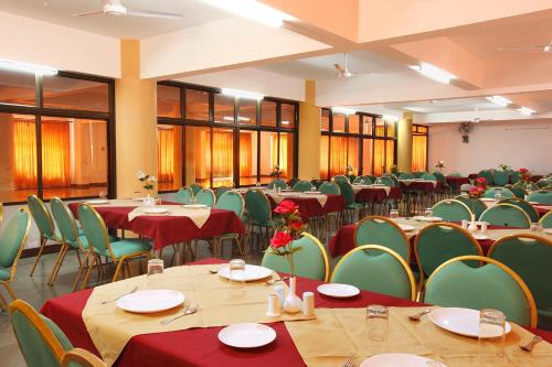 une salle de banquet avec des tables et des chaises vertes dans l'établissement Rajavalsam Guruvayur, à Guruvāyūr