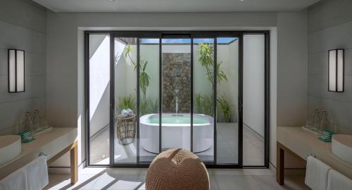 a bathroom with a tub with plants in it at Avani+ Barbarons Seychelles in Grand'Anse