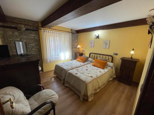 1 dormitorio con 1 cama con almohadas de color naranja en El Hayedo de Argovejo, en Argovejo