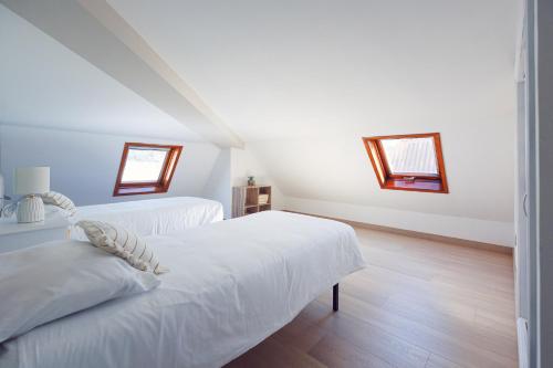 two beds in a white room with two windows at Chelsea Cedeira VIVIENDAS USO TURISTICO in Cedeira