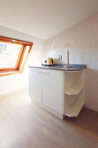 a white kitchen with a counter and a window at Chelsea Cedeira VIVIENDAS USO TURISTICO in Cedeira