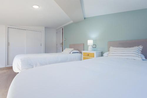 two beds in a white room with two beds at Chelsea Cedeira VIVIENDAS USO TURISTICO in Cedeira