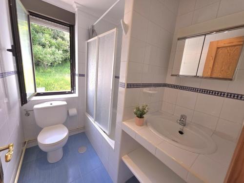 a bathroom with a toilet and a sink and a window at La Casa de Lidya - 36801 in Entrambasaguas