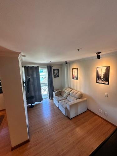 a living room with a white couch and a television at Barra da Tijuca - 508 - De Frente para Maravilhosa Piscina - Estacionamento Gratuito - Academia Comphania Atletica - Balsa para Praia Grátis - Microondas - Geladeira Grande - Recepção 24horas - Wi-Fi - Com Pia in Barra da Tijuca