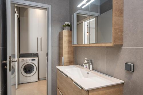 a bathroom with a sink and a washing machine at Argostoli Haven - Luxury House in Argostoli