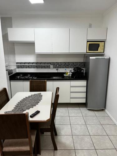 a kitchen with a table and a stove and a refrigerator at AP 100m do mar mesma rua do Quiosque VavaZão in Capão da Canoa