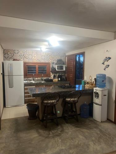 a kitchen with a counter and two bar stools at KiteHouseArpoeiras in Acaraú