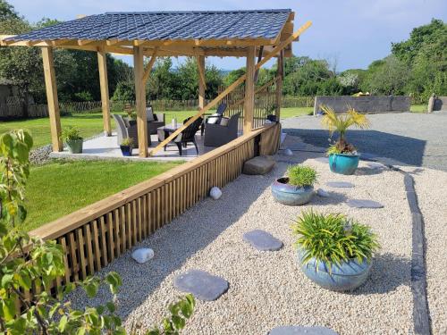 a wooden gazebo with chairs and potted plants at Maison de Coton Ty Koton in Plourivo
