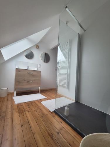 a bathroom with a glass shower and a wooden floor at Maison de Coton Ty Koton in Plourivo