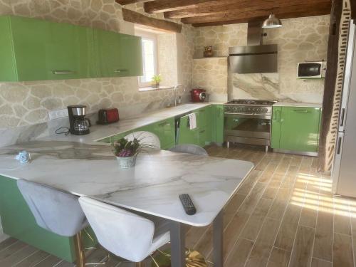 une cuisine avec des placards verts et une table avec des chaises dans l'établissement Gîte de villiers, à Saint-Julien-de-Chédon