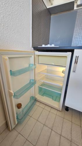 un réfrigérateur vide avec sa porte ouverte dans une cuisine dans l'établissement Studio - 2min Mer & Plages - Grau du Roi, au Grau-du-Roi