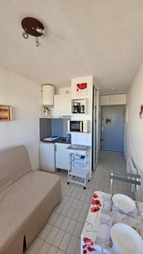 un salon avec un canapé et une cuisine dans l'établissement Studio - 2min Mer & Plages - Grau du Roi, au Grau-du-Roi