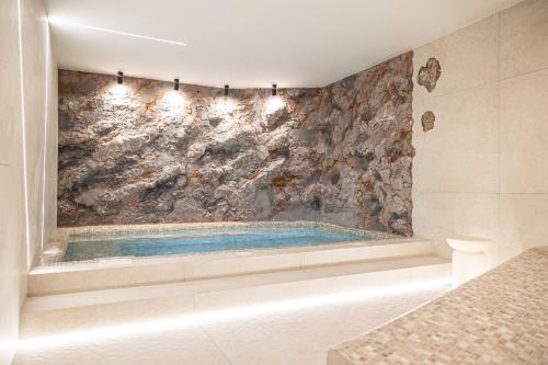 a bathroom with a tub with a stone wall at Olea Luxury Rooms & Spa in Split