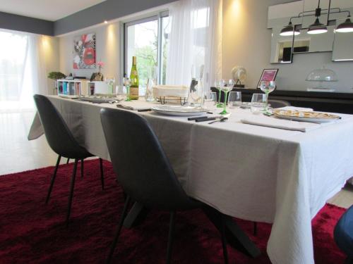 a long table with a white tablecloth and chairs at Kerwall - Maison d'hôtes in Malville