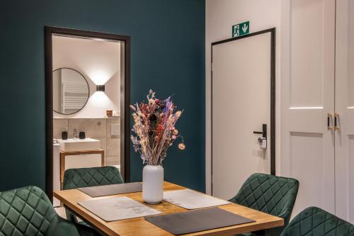 a dining room table with green chairs and a vase with flowers at Oran Apartment 3 in Berlin