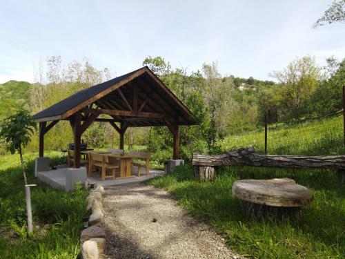 a wooden pavilion with a table in a field at ZAMURA Casa in Bozioru