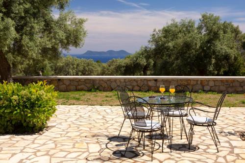 a glass table with chairs and two wine glasses on it at Lefkolia Retreat in Sivota