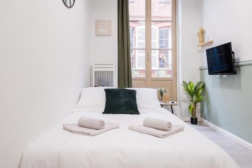 une chambre avec un lit blanc avec deux oreillers dessus dans l'établissement Le Petit Boulbone, à Toulouse