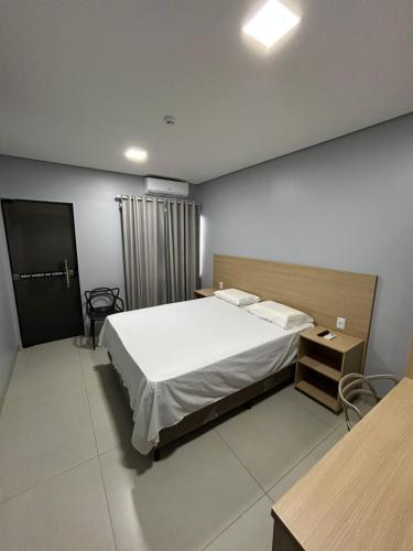 a bedroom with a large white bed and a table at Hotel Vizon 3 in Vilhena