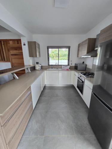 a large kitchen with white cabinets and a sink at Carlos Villa Poolside in Tamarin