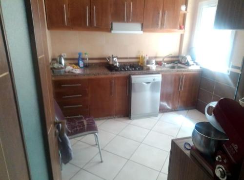 una cucina con mobili in legno, un lavello e una lavastoviglie di إقامة الصابرين تطوان a Tétouan