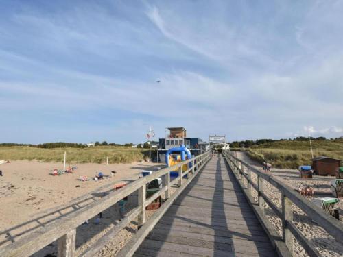 a wooden boardwalk leading to a beach with people on it at Wohnung mit großem Garten an der Ostseeküste in Neubukow
