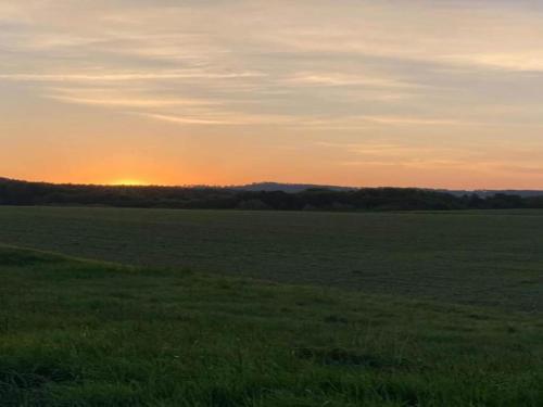 a field of grass with the sunset in the background at Lichtenhain Family Fun in Lichtenhain