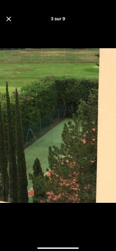 une vue d'un terrain de golf avec des arbres et une clôture dans l'établissement Appartement saisonnier, à Mandelieu-la-Napoule