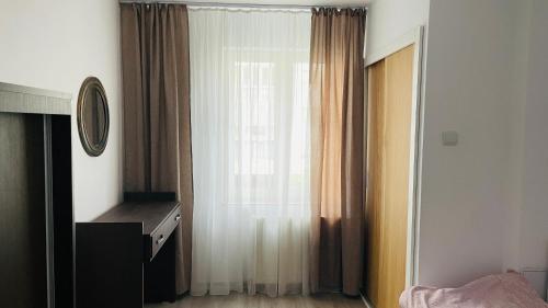 a bedroom with a window with curtains and a dresser at Boulevard apartament in Sighetu Marmaţiei