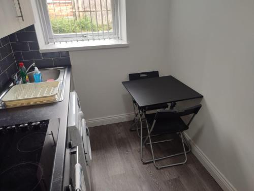 a small kitchen with a black table in the corner at Gosford Park Studio 4 - Coventry in Coventry