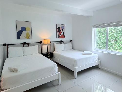 a white room with two beds and a window at Renzzi Villas in Miami