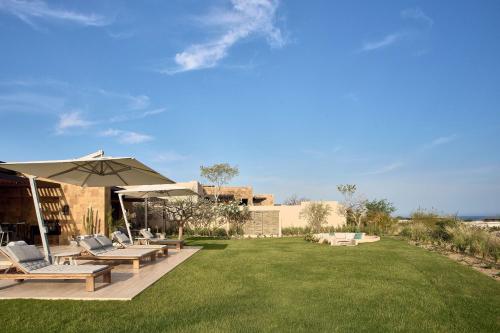 a yard with chairs and an umbrella and a lawn at Zadún, a Ritz-Carlton Reserve, Los Cabos in San José del Cabo
