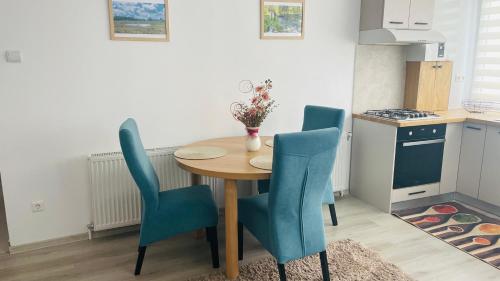 a kitchen with a wooden table and blue chairs at Boulevard apartament in Sighetu Marmaţiei