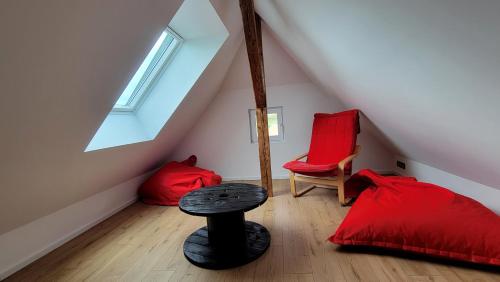 une chambre mansardée avec deux lits rouges et une table dans l'établissement Gîte de la Chapelle - Le Bi jou, à Innenheim