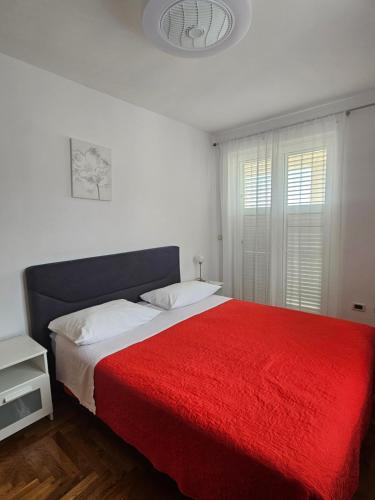 a bedroom with a large bed with a red blanket at Apartment Mary in Trogir