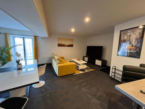 - un salon avec un canapé jaune et une télévision dans l'établissement L'appart écran Géant, à Joinville