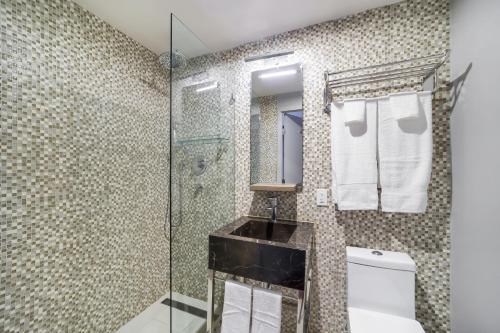 a bathroom with a glass shower and a toilet at Alamo Hotel in Miami Beach