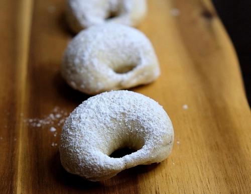 four sugar covered donuts on a wooden cutting board at Villa Mirella in Villalfonsina