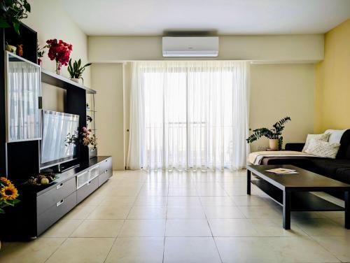 a living room with a couch and a tv at Sunset Haven Manikata - Walking distance to Golden Bay in Manikata