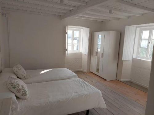 1 dormitorio blanco con 2 camas y 2 ventanas en Casa Castro, en Lamas